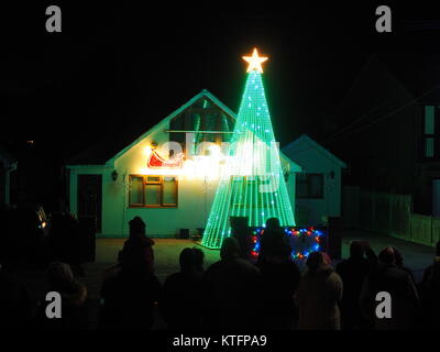 Warden Bay, Kent, Regno Unito. 24 dicembre, 2017. Una casa in Warden Bay mette su una spettacolare la vigilia di Natale display luci dotate di una struttura realizzata da luci più alti di quelli della casa che visualizza varie controllate dal computer degli schemi di illuminazione a tempo di musica. Circa 75-100 persone uscì a guardare il display a 7pm, che dura per circa 30 minuti. Tutte le donazioni sono date per il SNAAP (Esigenze particolari Advisory & Attività Progetto) di carità per bambini disabili. Credito: James Bell/Alamy Live News Foto Stock