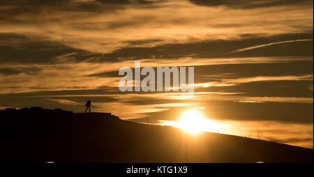 Horben, Germania. 25 Dic, 2017. Un uomo cammina su una collina innevata al tramonto vicino a Horben, Germania, 25 dicembre 2017. Credito: Patrick Seeger/dpa/Alamy Live News Foto Stock