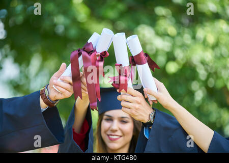 Istruzione, graduazione e concetto di persone - gruppo di felice gli studenti internazionali in mortaio e schede di corso di laurea gli abiti con diplomi Foto Stock