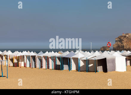 Praia da Nazare beach a Nazare, Portogallo, coperto con la stagione estiva spiaggia tende. Foto Stock