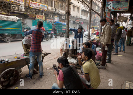 Uomo di ottenere capelli tagliati fuori nella vecchia Delhi street scene, New Delhi, India Foto Stock