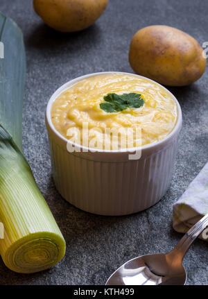 Pronto a mangiare vegetariano e patate Zuppa di porri sul tavolo in pietra circondato da ingredienti Foto Stock