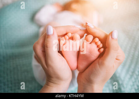 Capogruppo holding nelle mani dei piedi del neonato. Foto Stock