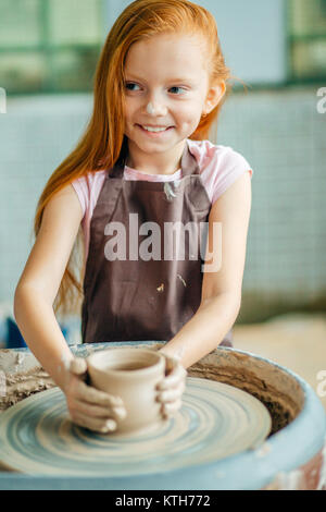 Redhead fanciullo scolpisce dalla pentola di creta. Workshop sulla modellazione sul tornio del vasaio. Foto Stock