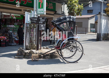 ITSUKUSHIMA, Giappone-CIRCA APR, 2013: Rickshaw a due ruote carrello passeggero è su strade di Miyajima. Tirate il rickshaw è una famosa forma di trasporto Foto Stock