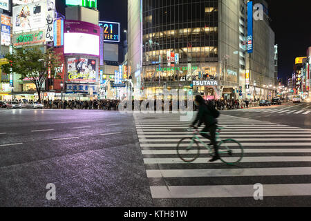 TOKYO, Giappone - CIRCA APR, 2013: il ciclista che scotta sul vuoto incrocio stradale. Shibuya Crossing è luogo famoso per la traversata scramble. Vista notturna a ped Foto Stock