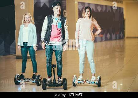 Uomo e donna due a cavallo su hoverboard in mall Foto Stock