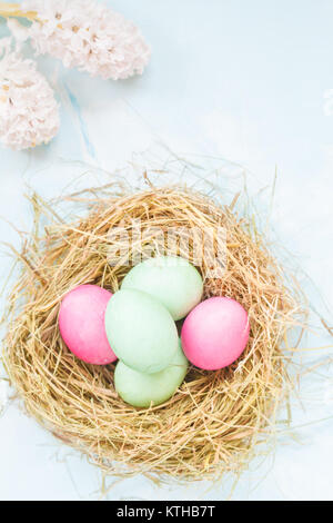 Colorate le uova di Pasqua nel nido e fiori. Spazio per il testo. Luce festosa decorazione di Pasqua. Festival di Pasqua di concetto. Foto Stock