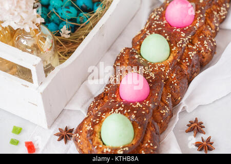 Greco tradizionale pane di Pasqua - tsoureki nelle decorazioni di Pasqua con uova dipinte e fiori. Festival di Pasqua di concetto. Foto Stock