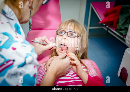 Frightened sweet little girl con bocca aperta è in studio dentistico, cure dentarie. Foto Stock