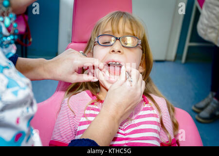 Frightened sweet little girl con bocca aperta è in studio dentistico, cure dentarie. Foto Stock