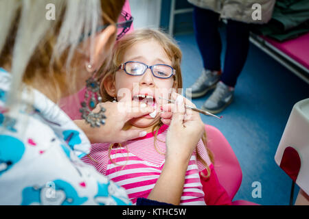 Frightened sweet little girl con bocca aperta è in studio dentistico, cure dentarie. Foto Stock