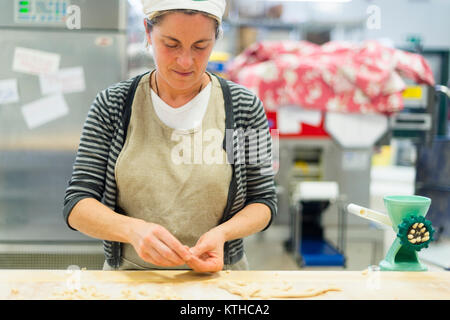 Donna fare e preparare pisarei gnocchi di pasta tipico da Emilia Romagna, Piacenza, Italia presso il ristorante cucina preparazione Foto Stock