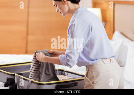 Caparra focalizzata donna prendendo i suoi vestiti dal bagaglio Foto Stock