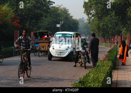 Un ciclista che indossa gli auricolari in movimento nella parte anteriore di un furgone elettrico che stava trasportando i turisti dal Taj Mahal porta orientale di Shilpgram in Agra, Uttar Pradesh. Foto Stock