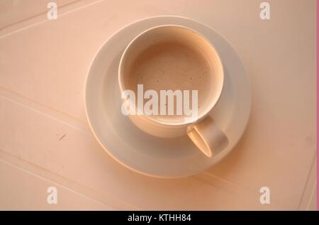 Un caldo il caffè amaro su un bianco tavolo di plastica con un cucchiaio e piattino sotto in attesa di qualcuno a bere in una zolla di terreno meteo nel dicembre 2017. Foto Stock