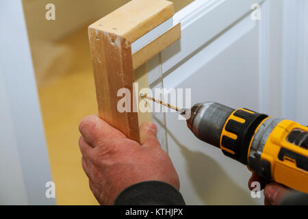 Assemblaggio di mobili da trapani chipboardsnd porta dell'armadio, utilizzando un cacciavite a batteria, vicino. Foto Stock