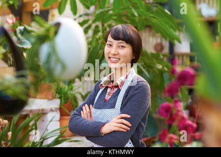 Una bellissima donna cinese a lavorare nel fioraio sorriso alla fotocamera Foto Stock