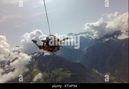 Questo lo skydiving in tandem e team sta godendo il volo panoramico su una bella montagna e lago di zona. Check out la faccina sorridente dal passeggero! Foto Stock