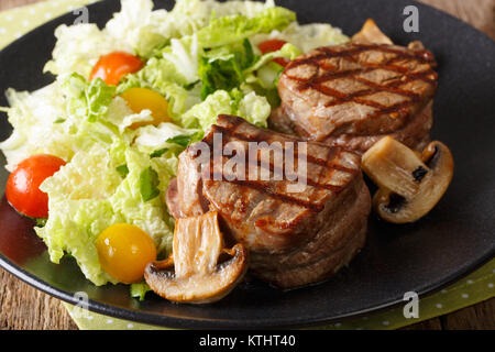 Deliziosi minion di filetto di manzo con verdure fresche e insalata di funghi close-up su una piastra orizzontale. Foto Stock