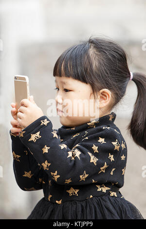 Xian,Cina - Ottobre 22,2017: bambina gioca con l'iphone sulla strada a ottobre 22, in Cina. Foto Stock