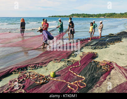 L'immagine mostra un gruppo di individui che si occupano di reti a Ilocos Norte, Filippine. L'attività fa parte della cultura della pesca della regione, dove le reti vengono utilizzate per le pratiche di pesca locali e per il sostentamento economico. Foto Stock