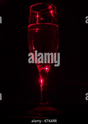 Bicchiere di vino un bicchiere di champagne in raggi del laser rosso. Ancora in vita. Foto Stock