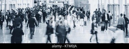 Folla di offuscata la gente di affari ad una fiera commerciale piano Foto Stock