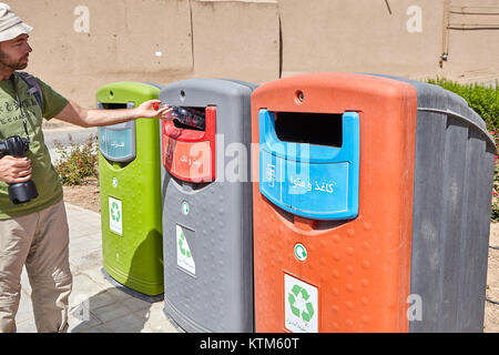 Yazd, Iran - 22 Aprile 2017: il turista utilizzati contenitori per la raccolta differenziata dei rifiuti, gettando una bottiglia di plastica nel contenitore appropriato. Foto Stock