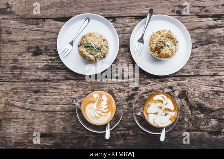 Due tazze di cappuccino di aroma di legno sfondo testurizzata con muffin, spazio vuoto per il testo, laici piatta Foto Stock