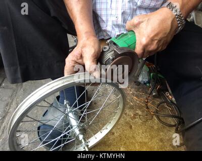 La macchina di rettifica funziona e scintillante con ruota di bicicletta da maschio. Foto Stock