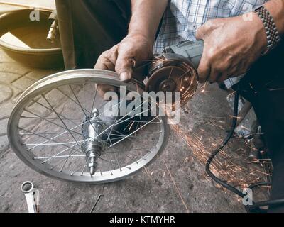 La macchina di rettifica funziona e scintillante con ruota di bicicletta da maschio. Foto Stock