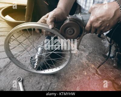 La macchina di rettifica funziona e scintillante con ruota di bicicletta da maschio. Foto Stock