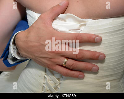 Vicino la mano di sposo sul retro della sposa in bianco abito da sposa Foto Stock