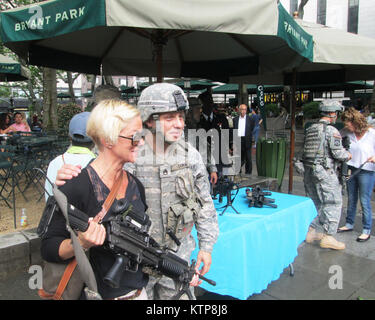 NEW YORK-- New York esercito nazionale del personale di guardia Sgt. Daniel Dukin pone con un visitatore di armi ed equipaggiamento visualizzare il primo battaglione di fanteria 69presentati in Bryant Park il Venerdì, 13 giugno come parte degli eventi per commemorare il 239th compleanno dell'esercito degli Stati Uniti di Sabato 14 Giugno, 2014. Foto Stock