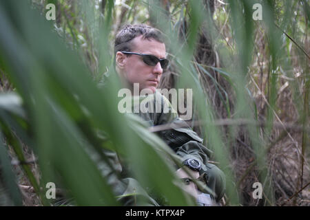 HOMESTEAD AIR BASE DI RISERVA, FLORIDA - Major Dave Sumwalt, un pilota con la 101st Rescue Squadron, tiene il coperchio durante un combattimento e acqua di sopravvivenza corso di formazione ad Homestead Air Base di riserva, Florida il 20 gennaio 2016. Durante questo corso di formazione, equipaggio membri guadagnato un training di aggiornamento utilizzando il proprio radio emergenza, movimenti tattici attraverso difficiult terreno, come costruzione di rifugi, modi di costruire gli incendi e i metodi per eludere il nemico. (US Air National Guard / Staff Sergente Christopher S. Muncy / rilasciato) Foto Stock