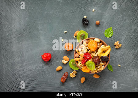 Varie la frutta secca e i dadi in una ciotola di ceramica (noce, anacardi, mandorle, pinoli, nocciole) su una pietra grigio ardesia o sfondo. Il concetto di un Foto Stock