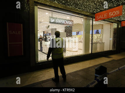 Una guardia di sicurezza sta in piedi di fronte ad una finestra infranta nella parte posteriore della House of Fraser su Oxford Street, Londra, a seguito di un precedente incidente. Foto Stock