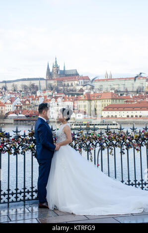 Praga Repubblica Ceca - 5 Dicembre 2017: Orientale giovane sposarsi a Charles Bridge di Praga con la Cattedrale di San Vito in background Foto Stock