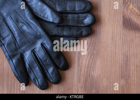 Coppia di uomini nero Guanti in pelle giacente su sfondo di legno Foto Stock