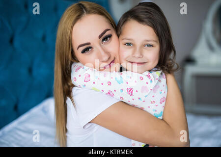 Madre e figlia godono nel letto di casa e guardando la telecamera. Foto Stock
