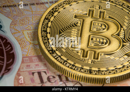 Oro moneta Bitcoin su un tenner dieci pound nota Foto Stock