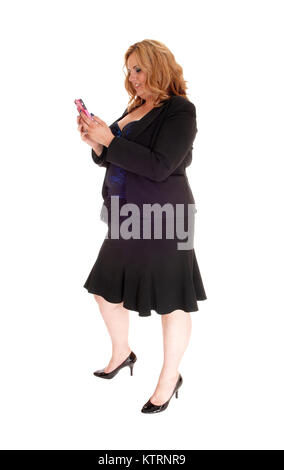 Una piena di dimensioni donna in piedi in un nero business suit in profilo isolato per sfondo bianco, sms sul suo telefono cellulare Foto Stock