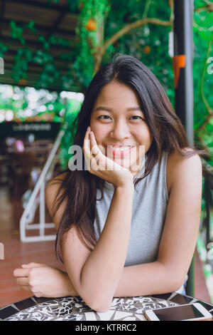 Carino asian Tailandese donne ritratto in seduta il cafe relax postura dentale con bel sorriso Foto Stock