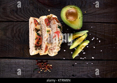 Il pane fatto in casa e rabboccato con funghi e pomodori secchi accanto a avocado e sale grosso su un legno rustico sfondo, fotografato da sopra'''' Foto Stock