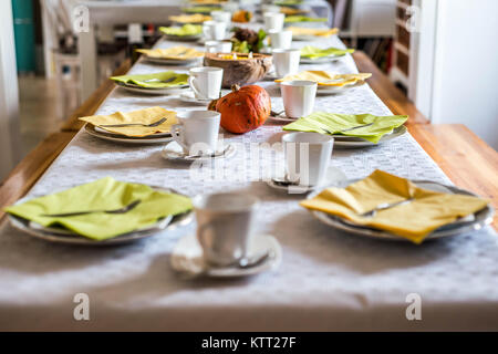 Bella cena di gala tabella colorata Giallo autunno helloween decorazione zucca tazze da caffè con piattini piastre e cucchiaio Foto Stock