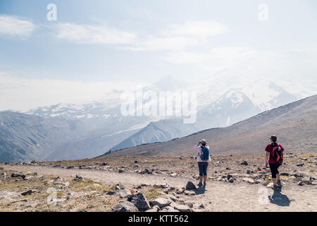 Due donne camminano lungo il sentiero di montagna, il Mount Rainier National Park, Washington, Stati Uniti Foto Stock