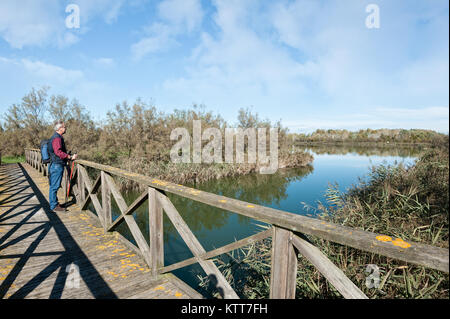 Escursionista (60 anni) su una passerella in legno sul fiume. Foto Stock