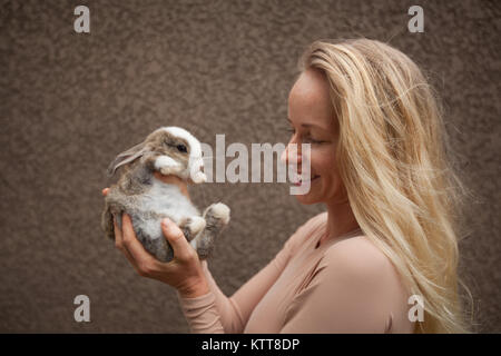 Idealista giovane donna bionda fantasticando con Natale bunny coniglio nelle sue mani Foto Stock