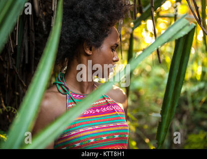 Il Melanesian pacific islander atleta ragazza con i capelli afro sytile nella giungla, profilo a metà Foto Stock